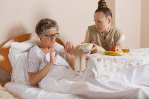 Starszy asystent opieki społecznej karmi starszą kobietę
